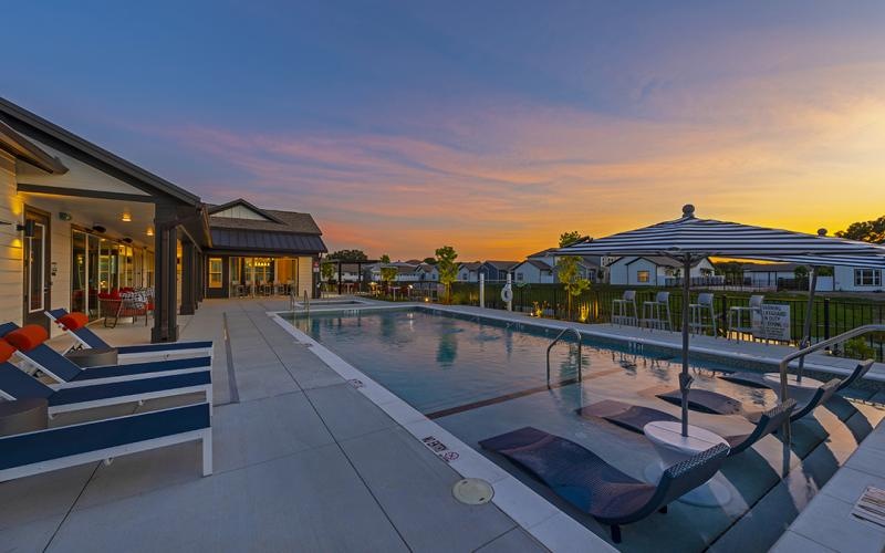 a swimming pool with lounge chairs at dusk