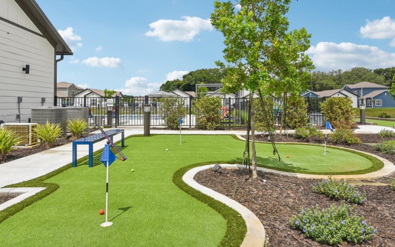 a putting green with a tree and a building
