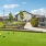 a large green lawn for bocce ball with a bench and a fence and a building